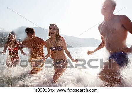 Stock Photo - Young friends splashing in the sea. Fotosearch