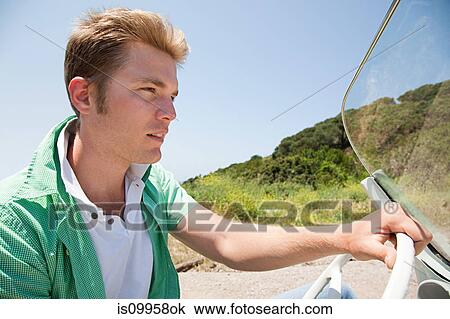Stock Image - Young man driving convertible car. Fotosearch