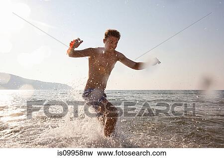 Young man splashing in sea View Large Photo Image Stock Photo - Young man splashing in sea. Fotosearch