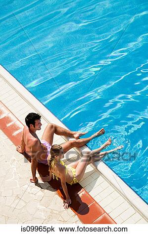 Young couple sitting at poolside View Large Photo Image Stock Image - Young couple sitting at poolside. Fotosearch