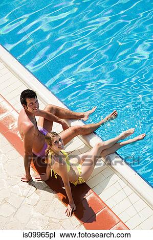 Young couple sitting at poolside View Large Photo Image Stock Image - Young couple sitting at poolside. Fotosearch