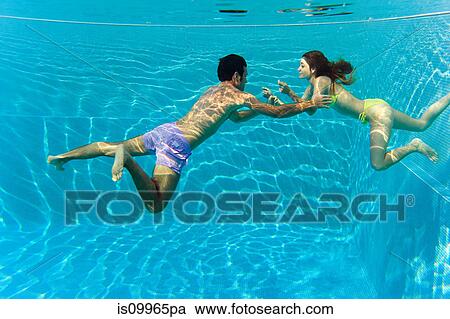Stock Image - Young couple swimming in swimming pool, underwater view. Fotosearch