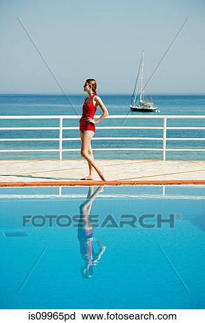 Stock Image - Young woman by swimming pool, portrait. Fotosearch
