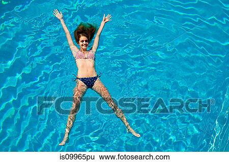 Young woman floating in swimming pool View Large Photo Image Stock Photograph - Young woman floating in swimming pool. Fotosearch