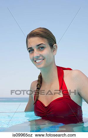 Stock Photo - Young woman in swimming pool, portrait. Fotosearch