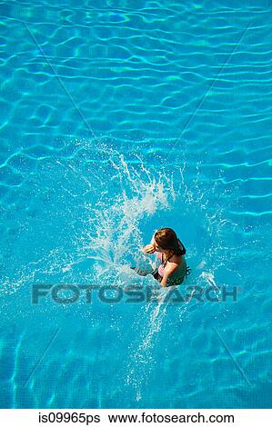 Stock Photograph - Young woman jumping into swimming pool. Fotosearch