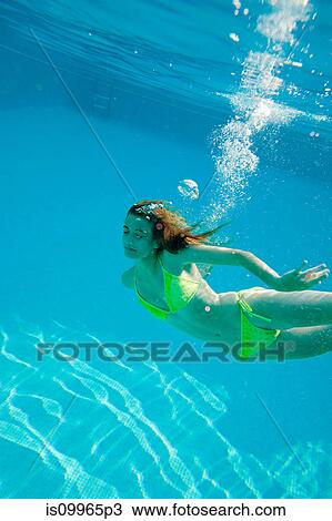 Young woman swimming underwater in swimming pool View Large Photo Image Stock Image - Young woman swimming underwater in swimming pool. Fotosearch