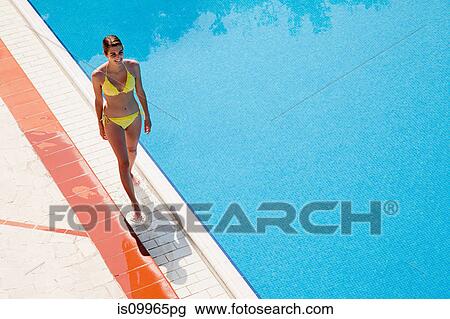 Young woman walking by poolside View Large Photo Image Stock Image - Young woman walking by poolside. Fotosearch