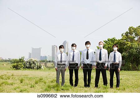 Stock Image - Businessmen in a row wearing pollution masks. Fotosearch