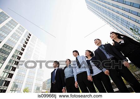Stock Image - Businesspeople in a row in city scene. Fotosearch