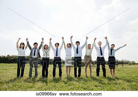Stock Photo - Businesspeople in a row in field, arms up. Fotosearch