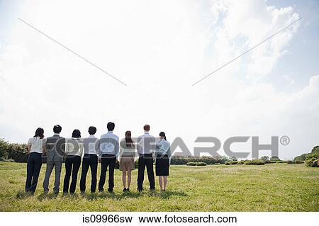 Businesspeople in a row in field, rear view View Large Photo Image Stock Photo - Businesspeople in a row in field, rear view. Fotosearch