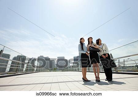 Stock Image - Businesswomen standing in city scene. Fotosearch