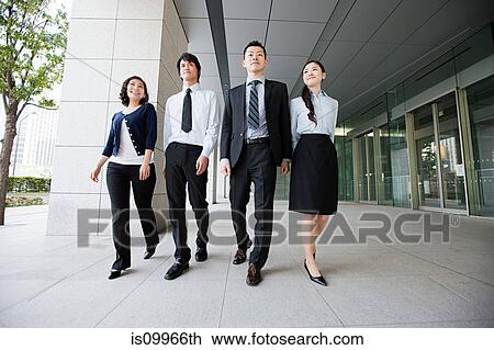 Stock Image - Four businesspeople on sidewalk. Fotosearch