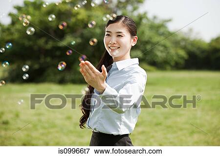Stock Photo - Portrait of young businesswoman touching bubbles. Fotosearch