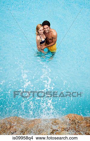 Young couple embracing in swimming pool, high angle View Large Photo Image Picture - Young couple embracing in swimming pool, high angle. Fotosearch