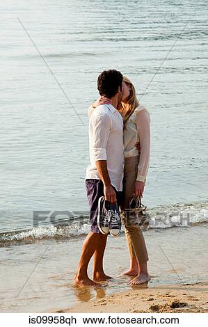 Stock Image - Young couple kissing on beach. Fotosearch