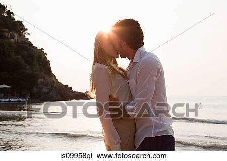 Stock Image - Young couple kissing on beach. Fotosearch