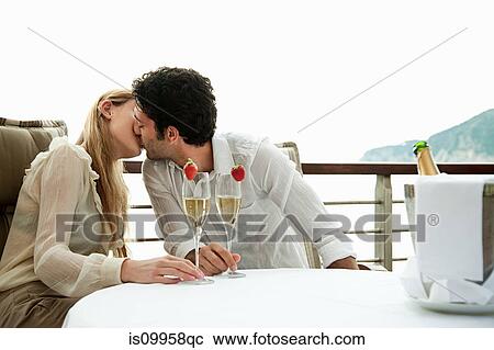 Stock Image - Young couple kissing with champagne. Fotosearch