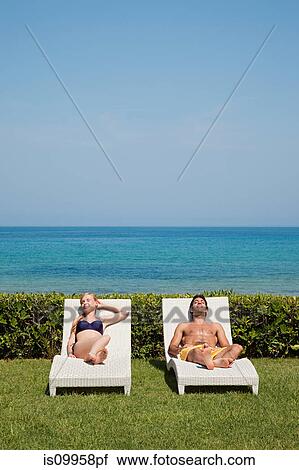 Stock Image - Young couple on sun loungers. Fotosearch