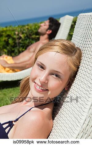 Young couple on sun loungers View Large Photo Image Stock Image - Young couple on sun loungers. Fotosearch