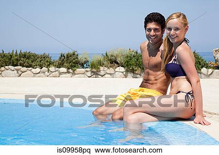 Young couple sitting at poolside View Large Photo Image Stock Photography - Young couple sitting at poolside. Fotosearch