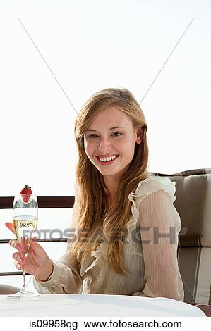 Young woman holding champagne flute, portrait View Large Photo Image Stock Image - Young woman holding champagne flute, portrait. Fotosearch