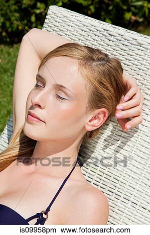 Picture - Young woman sleeping on sun lounger, close up. Fotosearch