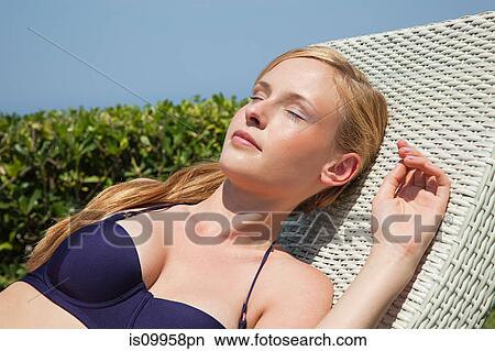 Picture - Young woman sleeping on sun lounger. Fotosearch