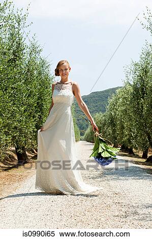 Bride on country road holding bouquet View Large Photo Image Stock Photography - Bride on country road holding bouquet. Fotosearch