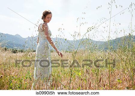 Bride wearing wedding dress alone in field View Large Photo Image Stock Image - Bride wearing wedding dress alone in field. Fotosearch