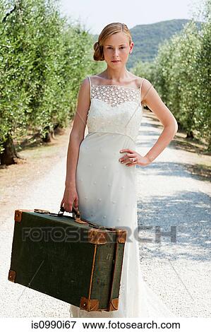 Bride with suitcase on country road, hand on hip View Large Photo Image Stock Photo - Bride with suitcase on country road, hand on hip. Fotosearch
