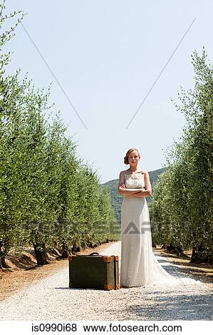 Bride with suitcase on country road, arms crossed View Large Photo Image Stock Photo - Bride with suitcase on country road, arms crossed. Fotosearch