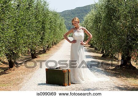 Bride with suitcase on country road, hands on hips View Large Photo Image Stock Photo - Bride with suitcase on country road, hands on hips. Fotosearch
