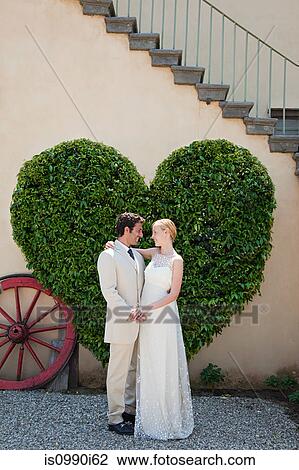 Newlyweds by heart shaped bush View Large Photo Image Stock Image - Newlyweds by heart shaped bush. Fotosearch