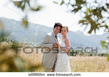 Newlyweds embracing in field View Large Photo Image Picture - Newlyweds embracing in field. Fotosearch