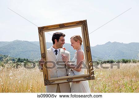 Stock Photo - Newlyweds holding vintage picture frame. Fotosearch