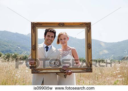 Newlyweds holding vintage picture frame View Large Photo Image Stock Photo - Newlyweds holding vintage picture frame. Fotosearch