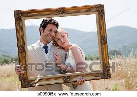 Newlyweds holding vintage picture frame View Large Photo Image Stock Photo - Newlyweds holding vintage picture frame. Fotosearch