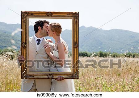 Newlyweds holding vintage picture frame, kissing View Large Photo Image Stock Photo - Newlyweds holding vintage picture frame, kissing. Fotosearch