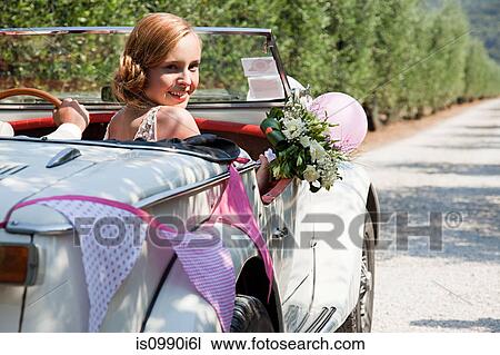 Stock Image - Newlyweds in classic car. Fotosearch