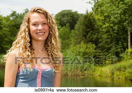 Portrait of a teenage girl smiling at camera with lake behind View Large Photo Image Stock Image - Portrait of a teenage girl smiling at camera with lake behind. Fotosearch