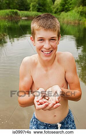 Teenage boy holding small reptile in hands by lake View Large Photo Image Stock Photograph - Teenage boy holding small reptile in hands by lake. Fotosearch