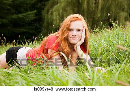 Teenage girl lying down on the grass chilling out View Large Photo Image Stock Photo - Teenage girl lying down on the grass chilling out. Fotosearch