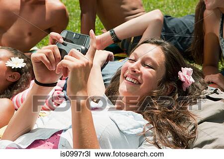 Teenage girl lying down with friends and looking at own camera pictures View Large Photo Image Stock Image - Teenage girl lying down with friends and looking at own camera pictures. Fotosearch