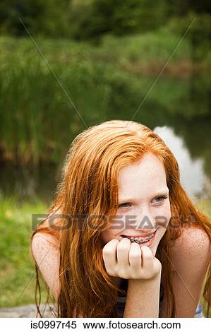 Stock Photography - Teenage girl smiling at friends with a lake behind her. Fotosearch