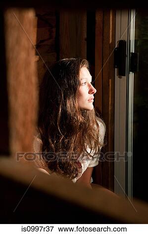 Teenage girl staring out of an open window View Large Photo Image Stock Photo - Teenage girl staring out of an open window. Fotosearch