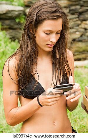 Stock Image - Teenage girl using mobile phone while chilling out. Fotosearch