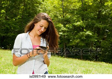 Teenage girl using mobile phone while walking in countryside View Large Photo Image Stock Photo - Teenage girl using mobile phone while walking in countryside. Fotosearch