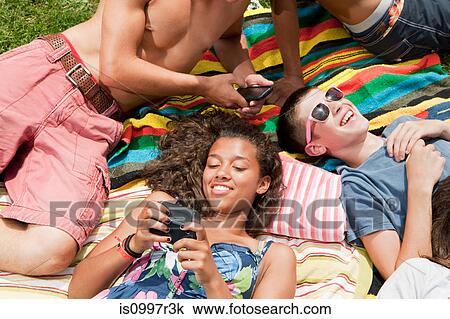 Teenagers chilling out on the grass on a hot summer's day View Large Photo Image Stock Image - Teenagers chilling out on the grass on a hot summer's day. Fotosearch